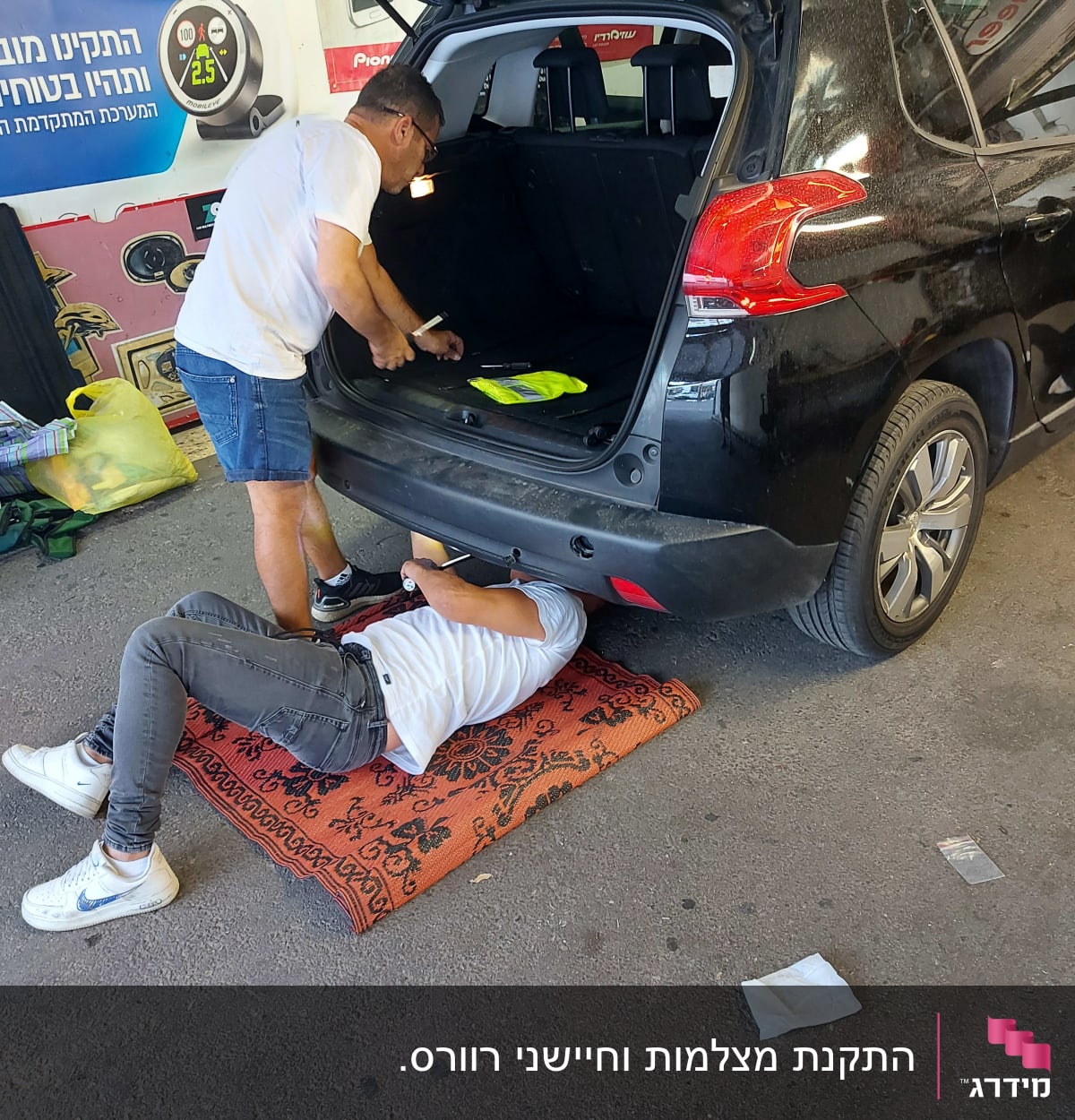 שני אנשים עובדים על רכב שחור בחניון